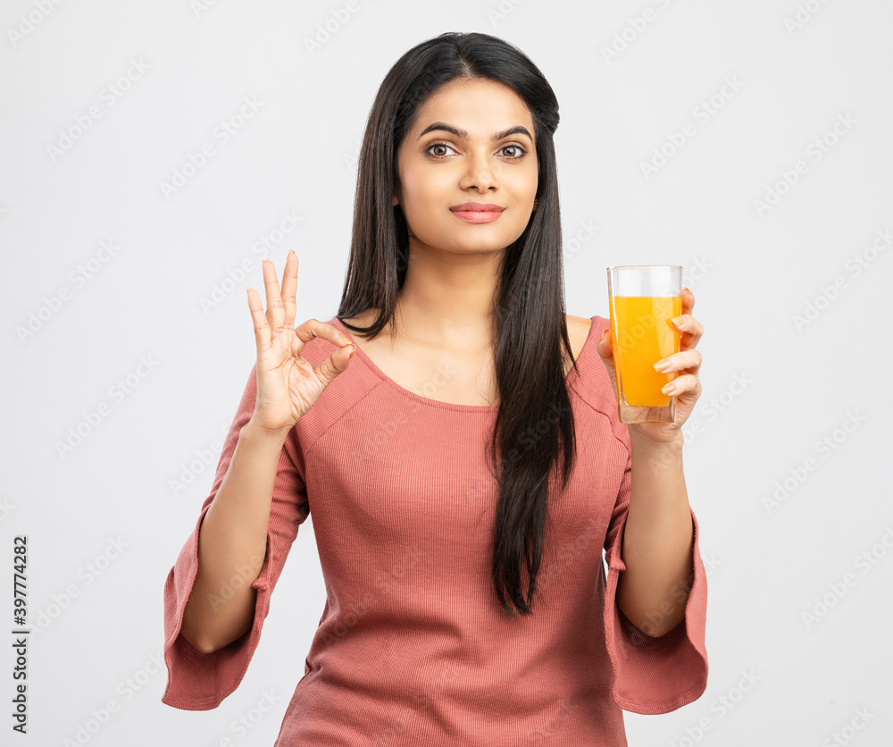 Pretty Indian young woman with orange juice on white. Pretty Indian young woman with orange juice on white.
