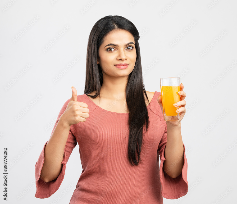Pretty Indian young woman with orange juice on white. Pretty Indian young woman with orange juice on white.
