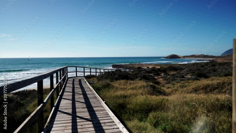 Coast landscape, rocky seashore with wooden path to sea water. Cala Magre beach in Calblanque Regional Park, Murcia region Spain. Coast landscape, rocky seashore with wooden path to sea water. Cala Magre beach in Calblanque Regional Park, Murcia region Spain.