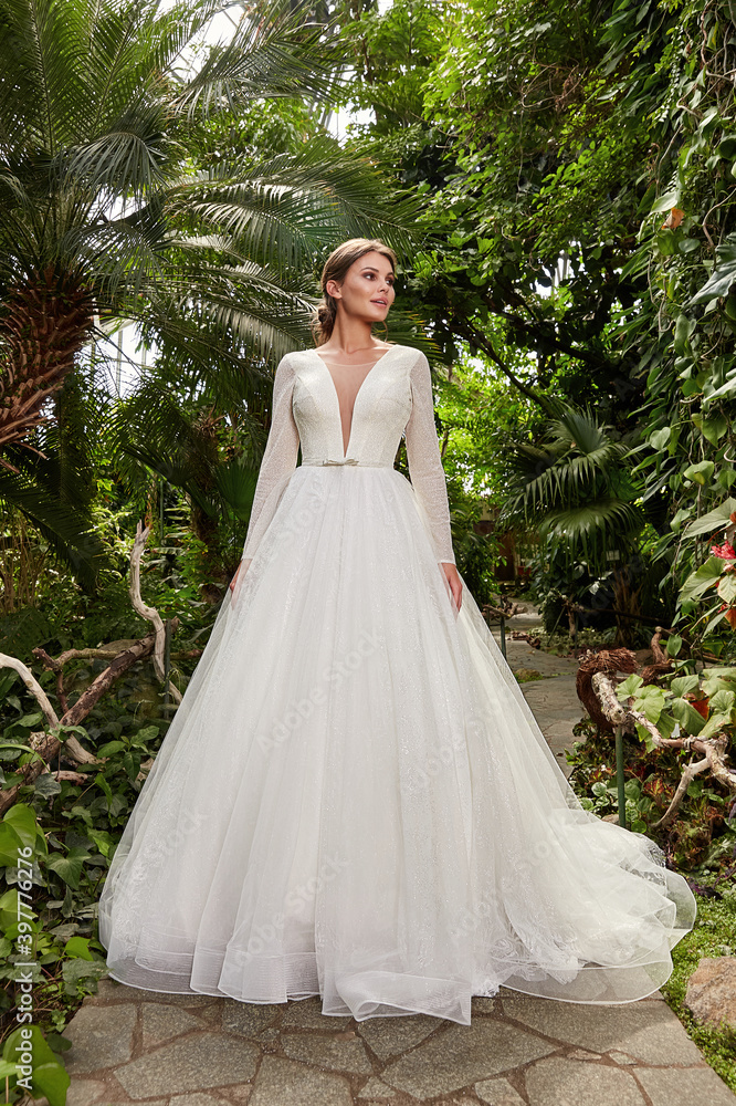 Beautiful sexy woman model bride wearing white long silk and lace wedding dress fashion espousal bright makeup brunette hairstyle ceremony in green summer garden love. Beautiful sexy woman model bride wearing white long silk and lace wedding dress fashion espousal bright makeup brunette hairstyle ceremony in green summer garden love.