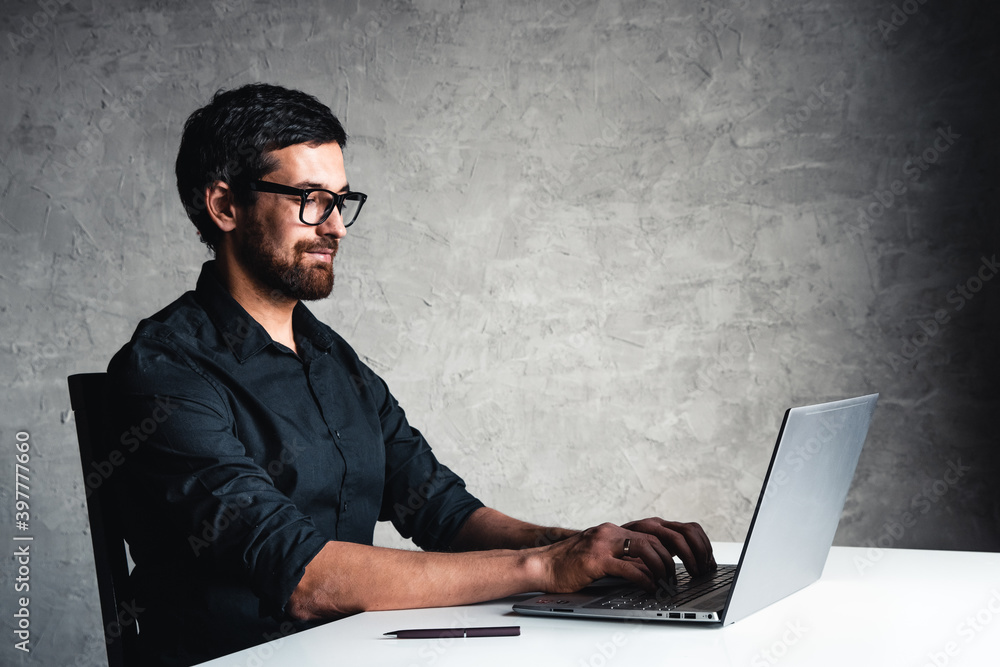 A man sits with a laptop in a black shirt. Business concept, work. Office routine. Property efforts A man sits with a laptop in a black shirt. Business concept, work. Office routine. Property efforts