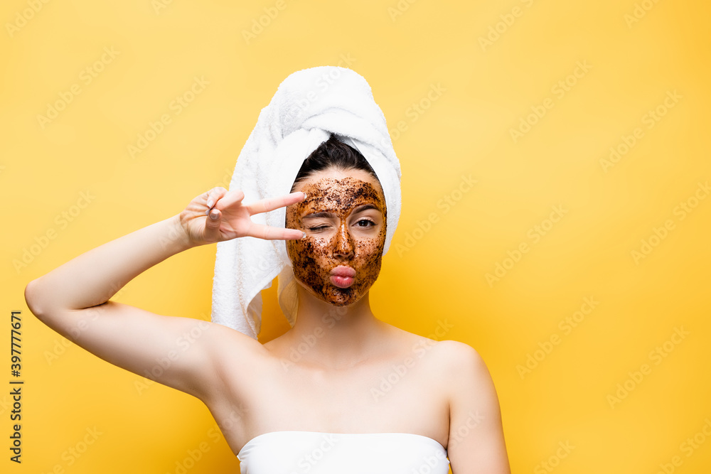 beautiful woman with towel on head and coffee mask on face grimacing isolated on yellow beautiful woman with towel on head and coffee mask on face grimacing isolated on yellow