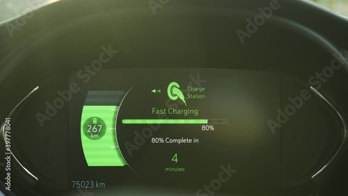 Electric car vehicle dashboard view during fast DC charging at power station. Green energy car interior view. Long range zero emission electric vehicle