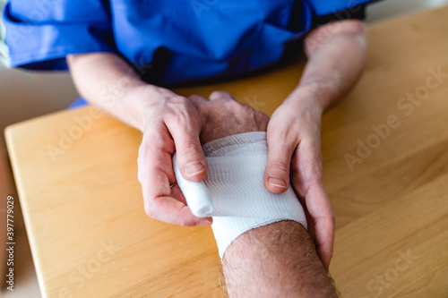Close-up of female nurse bandaging a hand or arm home care