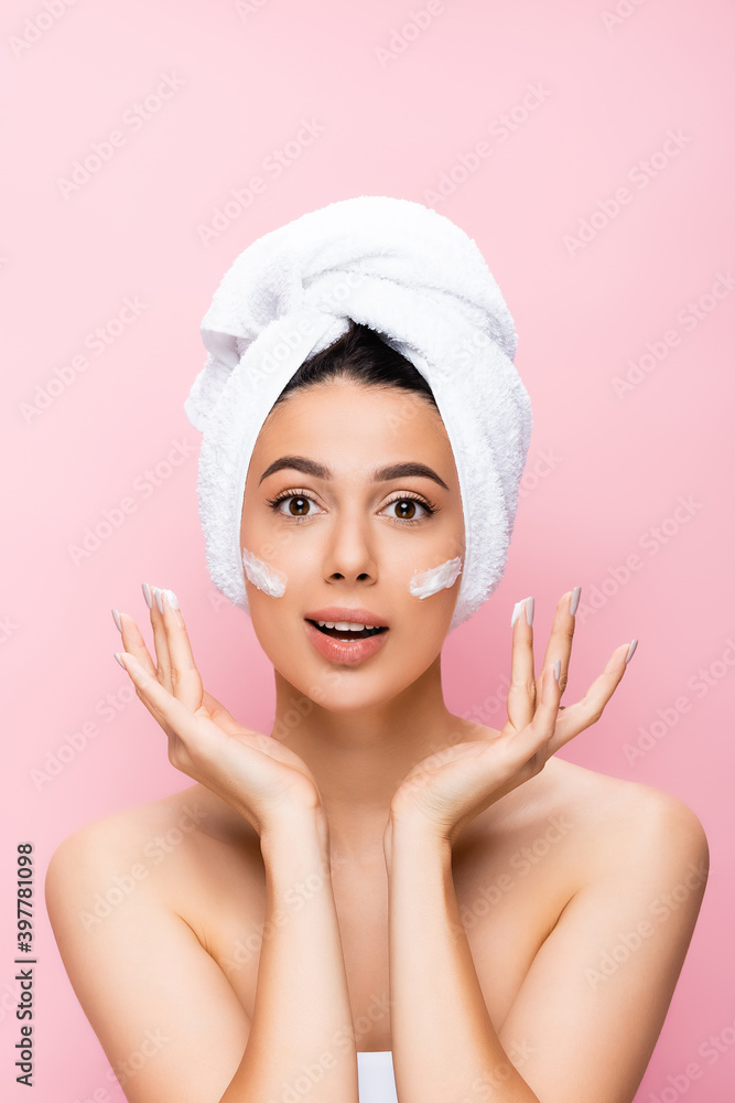 surprised beautiful woman with towel on hair and cosmetic cream on face isolated on pink surprised beautiful woman with towel on hair and cosmetic cream on face isolated on pink