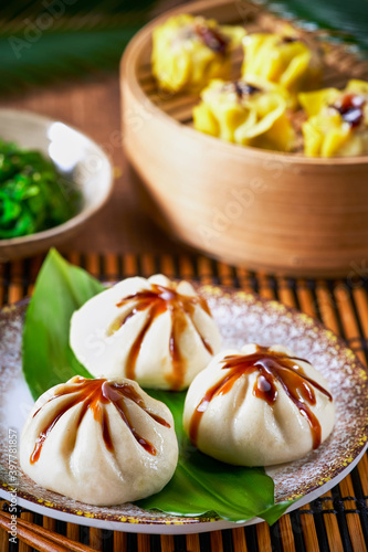 Photography Dumplings set Xiao long bao and Shao mai in bamboo steaming basket and chopsticks on bamboo mat