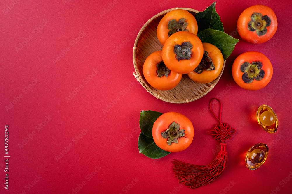 Top view of fresh sweet persimmons with leaves on red table background for Chinese lunar new year Top view of fresh sweet persimmons with leaves on red table background for Chinese lunar new year