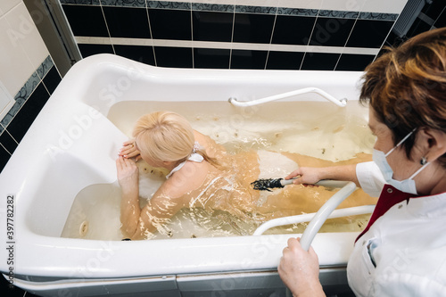 the procedure of underwater shower massage in the bathroom.Girl on the procedure of underwater massage photo