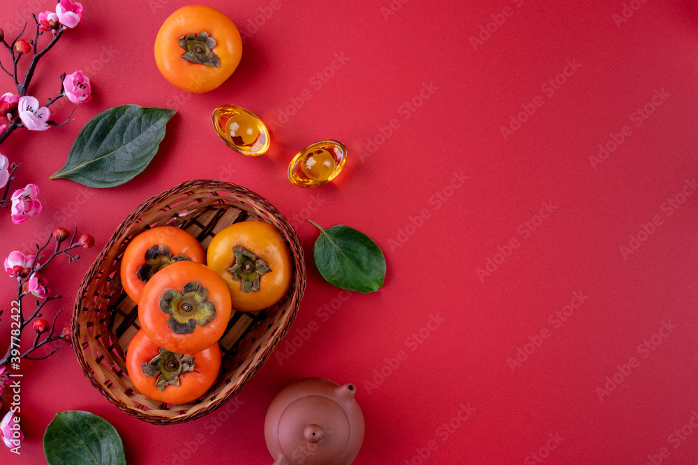 Top view of fresh sweet persimmons with leaves on red table background for Chinese lunar new year Top view of fresh sweet persimmons with leaves on red table background for Chinese lunar new year