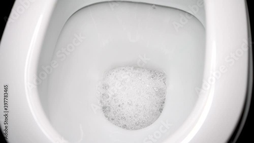 Flush the toilet close-up. White clean toilet, flushing water large
