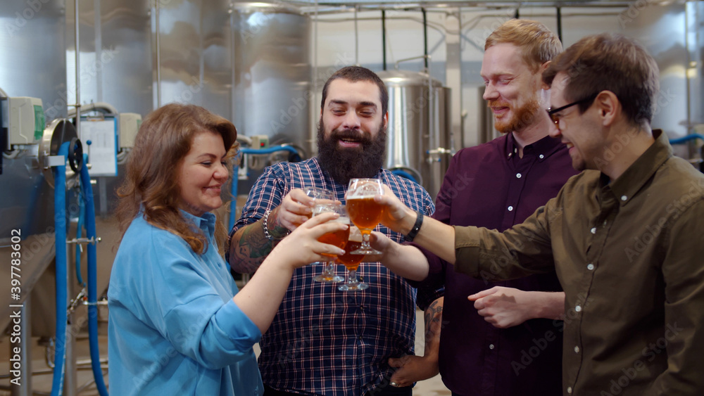 Young people clinking glasses of craft beer at brewery