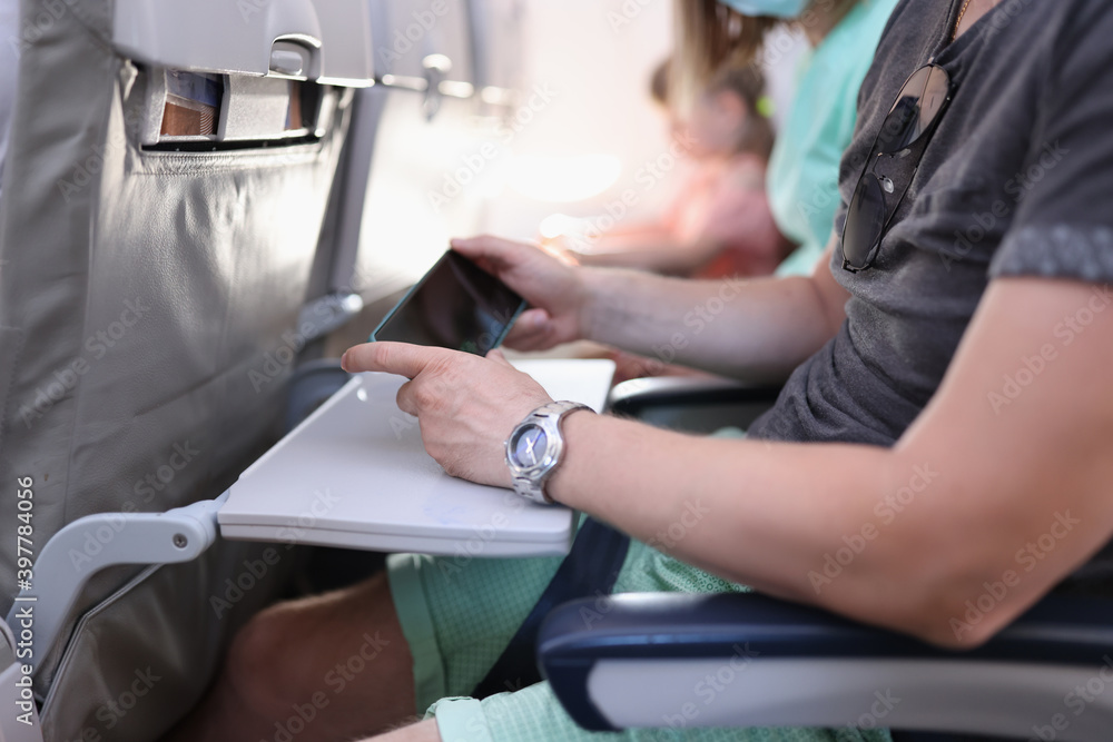 Passenger of plane sit still and hold phone in his hands. Safe and convenient flight for tourists with electronic technology services and Internet.