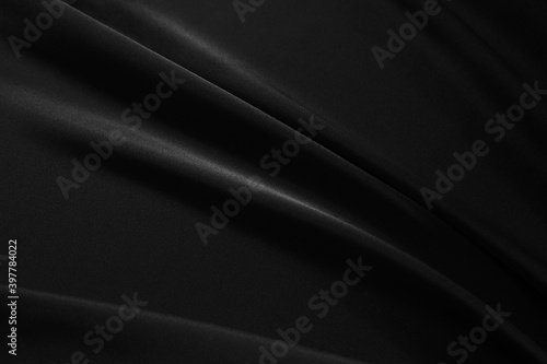 Black elegant background. Silk satin fabric with nice folds. Beautiful black background with wavy lines. Copy space.