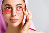 beautiful woman with towel on hair and hydrogel eye patches on face isolated on grey