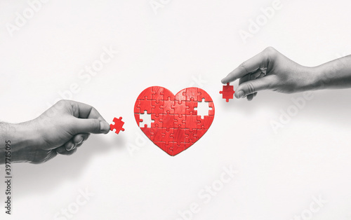 Two people put together a heart-shaped puzzle. The concept of building love relationships. photo