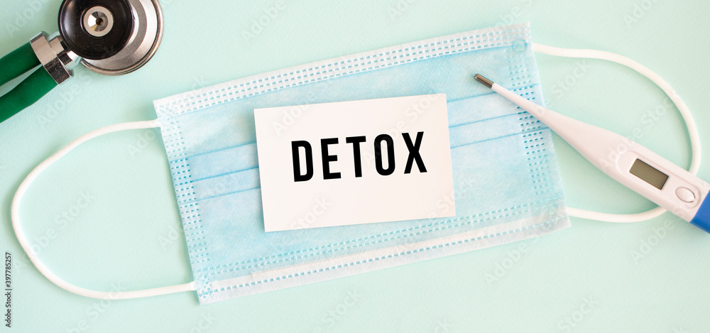 White card with the inscription DETOX on a medical protective mask. White card with the inscription DETOX on a medical protective mask.