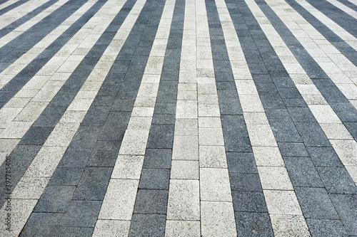 White and black paving slabs made of natural stone lined with stripes