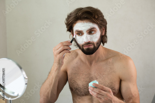 Close Up Of Man Using A Facial Mask. Close up of a cute caucasian man using a natural clay facial mask.