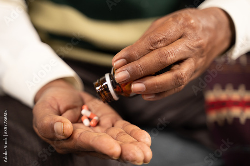 Close up of sick elder man hands taking tablets or pills