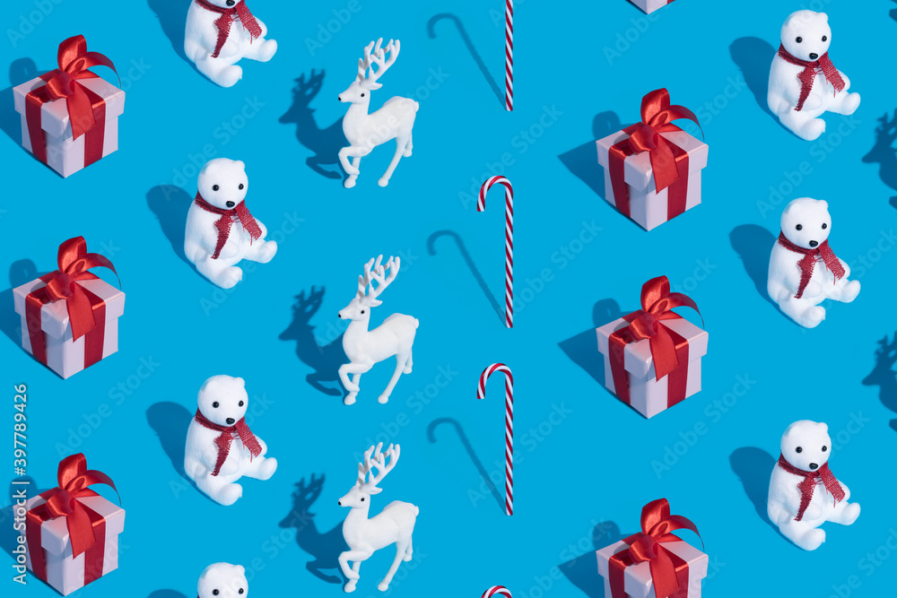 Christmas pattern made with polar bear, red gift box and reindeer on vibrant blue background. Minimal New Year festive celebration concept. Flat lay, top view. Christmas pattern made with polar bear, red gift box and reindeer on vibrant blue background. Minimal New Year festive celebration concept. Flat lay, top view.