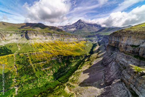 Green landscape in the Pyrenees of the Ordesa and Monte Perdido valley with mountains, rocks, forests and sky with clouds. Top aerial view. 