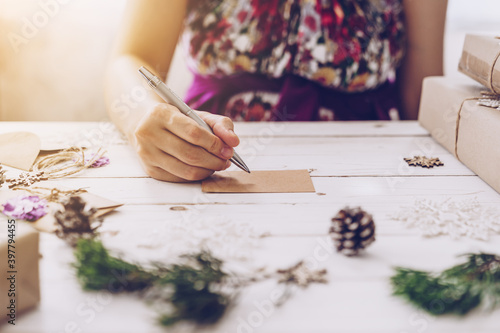 Woman hand writing beautiful Christmas card at table