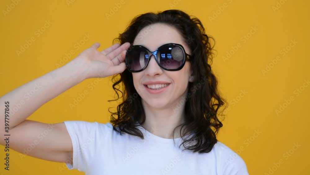 Cute girl portrait in sunglasses on a yellow background, laughs face Cute girl portrait in sunglasses on a yellow background, laughs face