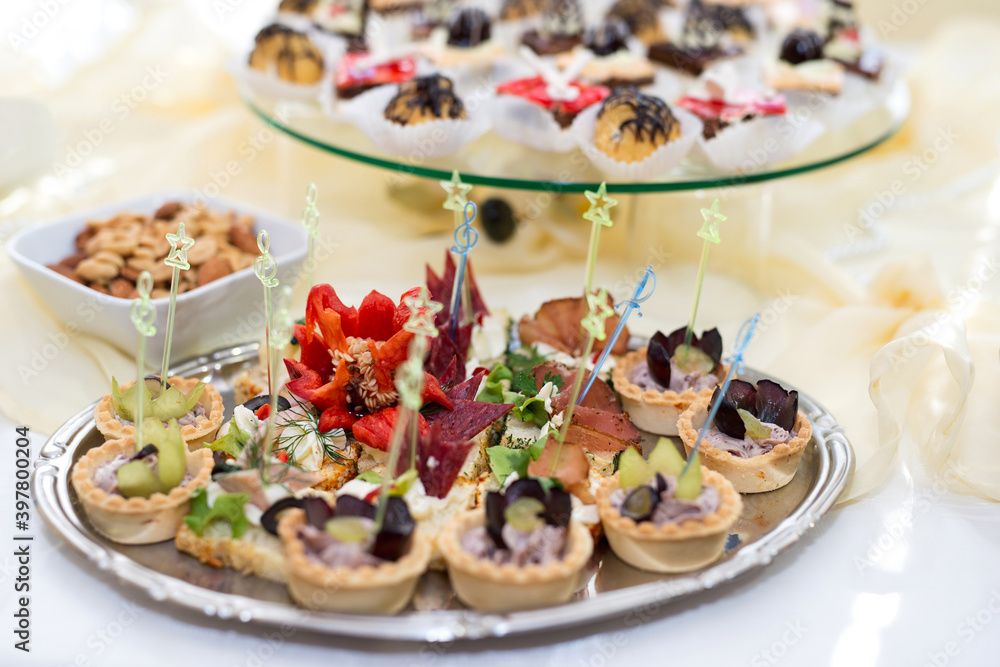 The buffet at the reception. Assortment of canapes on a table. Banquet service. Catering food, snacks with different types of cheese, ham, salami, prosciutto, shrimp, vegetables and fruits. The buffet at the reception. Assortment of canapes on a table. Banquet service. Catering food, snacks with different types of cheese, ham, salami, prosciutto, shrimp, vegetables and fruits.