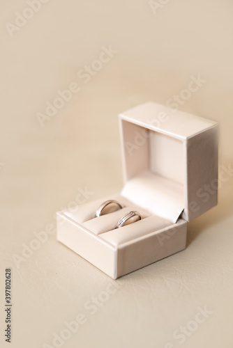 Close up of wedding rings in a light beige box over a light beige surface - selective focus, copy space.