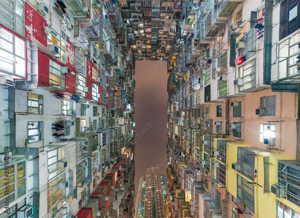 Exterior of crowded residential building in Hong Kong city at night. Building abstract background