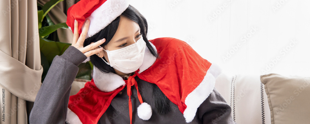 Obraz premium Unhappy Xmas woman in Santa clause suit having headache wearing face mask due to coronavirus and COVID-19 outbreak in Christmas period, concept of Covid Christmas or new normal social distancing Xmas