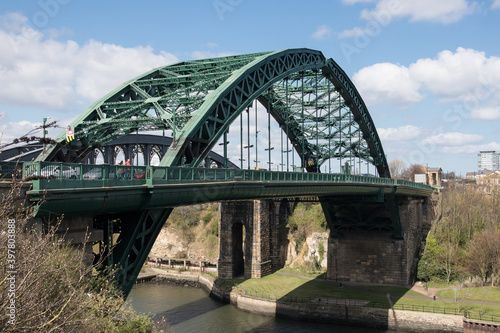 Old historic Victorian metal arched road bridge crossing spanning a river with blue sky
