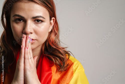 Focused beautiful woman wearing rainbow flag holding palms together