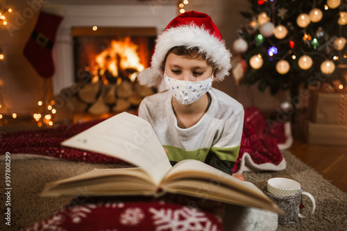 Boy meets Christmas in the covid-19 pandemic. Child in a protective medical mask. Quarantine isolation social distance. New year holidays.