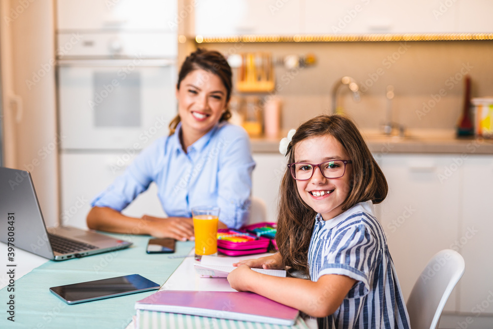 Cute little girl doing her homework, while her mother working from home due to coronavirus pandemic. Cute little girl doing her homework, while her mother working from home due to coronavirus pandemic.