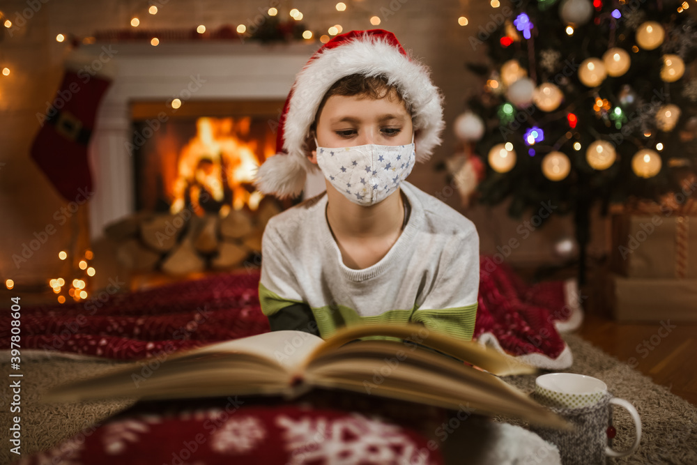 Boy meets Christmas in the covid-19 pandemic. Child in a protective medical mask. Quarantine isolation social distance. New year holidays. Boy meets Christmas in the covid-19 pandemic. Child in a protective medical mask. Quarantine isolation social distance. New year holidays.