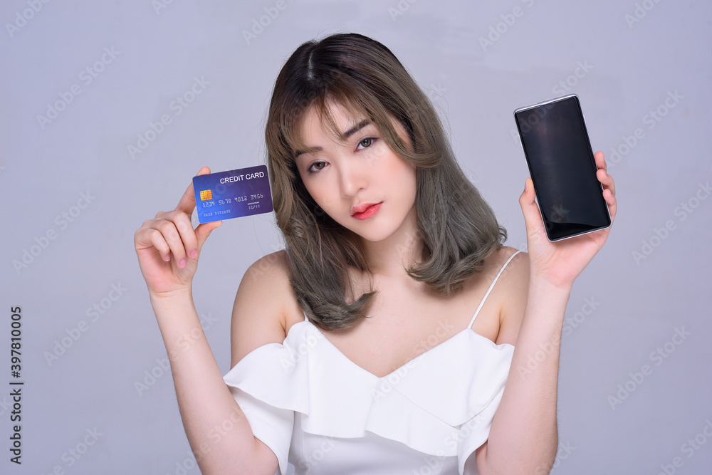 Portrait of young woman holding credit card and mobile phone Portrait of young woman holding credit card and mobile phone