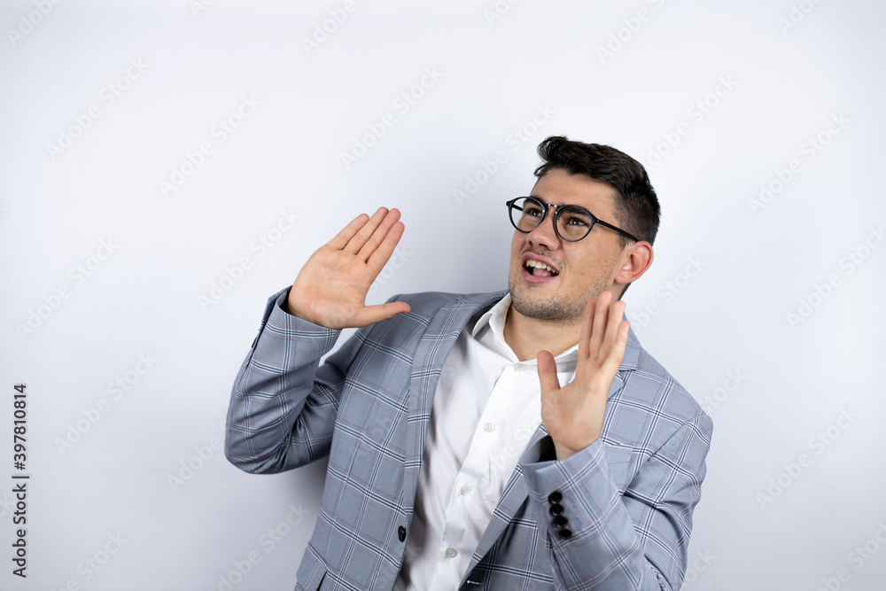 Business young man wearing a casual shirt over white background scared with her arms up like something falling from above Business young man wearing a casual shirt over white background scared with her arms up like something falling from above