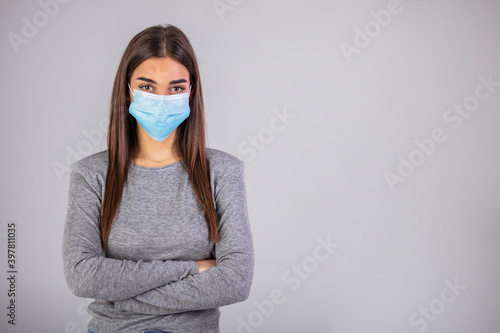 Beautiful young woman in white t-shirt with disposable face mask. Protection versus viruses and infection. Studio portrait, concept with gray background. Woman suffer from sick and wearing face mask.