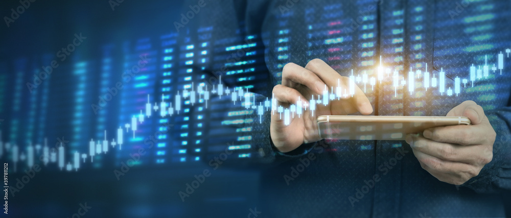 Fototapeta premium Hand holding smartphone device and touching screen. businessman trader looking on with graphs analysis candle