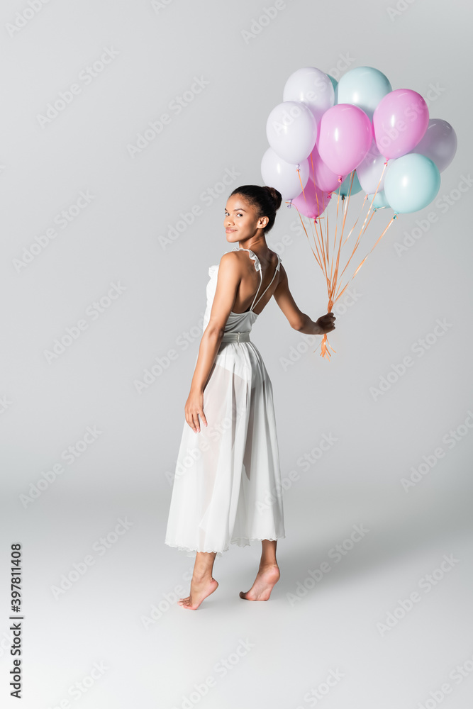 barefoot graceful african american ballerina in dress with balloons on white background barefoot graceful african american ballerina in dress with balloons on white background