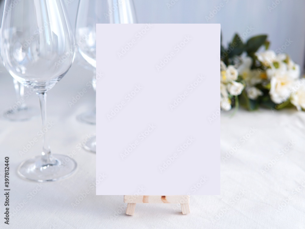Wedding bar menu template mockup, drinks menu on wooden easel,  white blank card and wine glasses  and flowers in background. - obrazy, fototapety, plakaty 