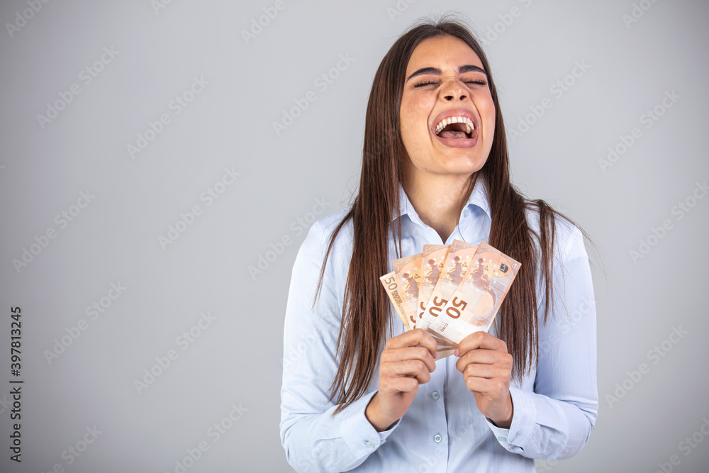 Portrait of a cheerful young woman holding money banknotes and celebrating isolated over gray background. Happy Woman Holding Euro Currency. Happy woman with lucky money. Portrait of a cheerful young woman holding money banknotes and celebrating isolated over gray background. Happy Woman Holding Euro Currency. Happy woman with lucky money.
