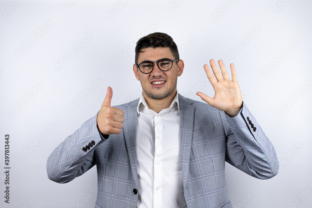 Business young man wearing a casual shirt over white background smiling confident and happy showing number six with fingers Business young man wearing a casual shirt over white background smiling confident and happy showing number six with fingers