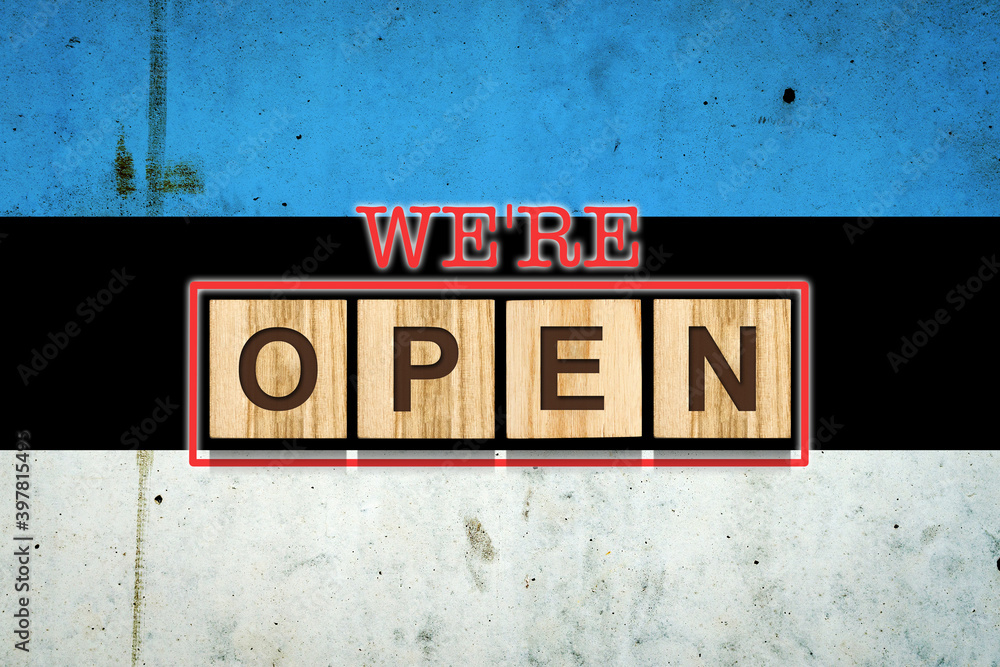 We are open. The inscription on wooden blocks against the background of the flag of Estonia. Business. We are open. The inscription on wooden blocks against the background of the flag of Estonia. Business.
