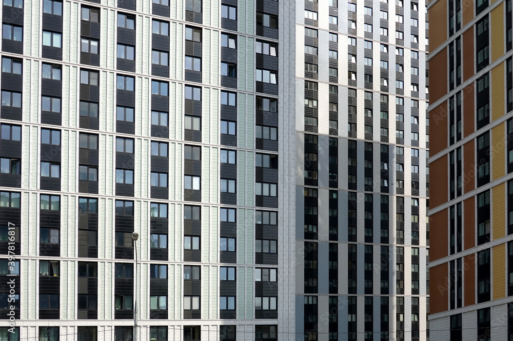 Fototapeta premium Close up front view of facades of modern buildings with many windows dense standing in the downtown area in a city