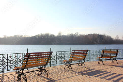 Bench on the lake in the park zone. Social distansing during pandemic. Empty park during covid-19 quarantine