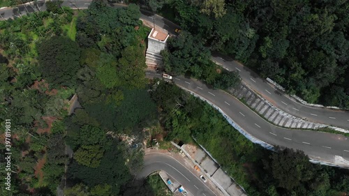 Hairpin bends in Yercaud, India covered with endless vast green forest with trees growing rapidly vehicles passing on the road top view.