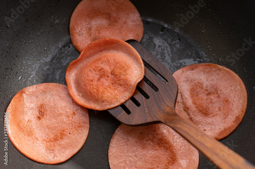 closeup frying pork bologna in black pan with small amount of cooking oil photo