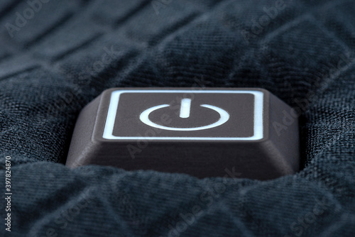 Macro shot of a plastic button with a white power symbol, sewn into modern clothing. photo